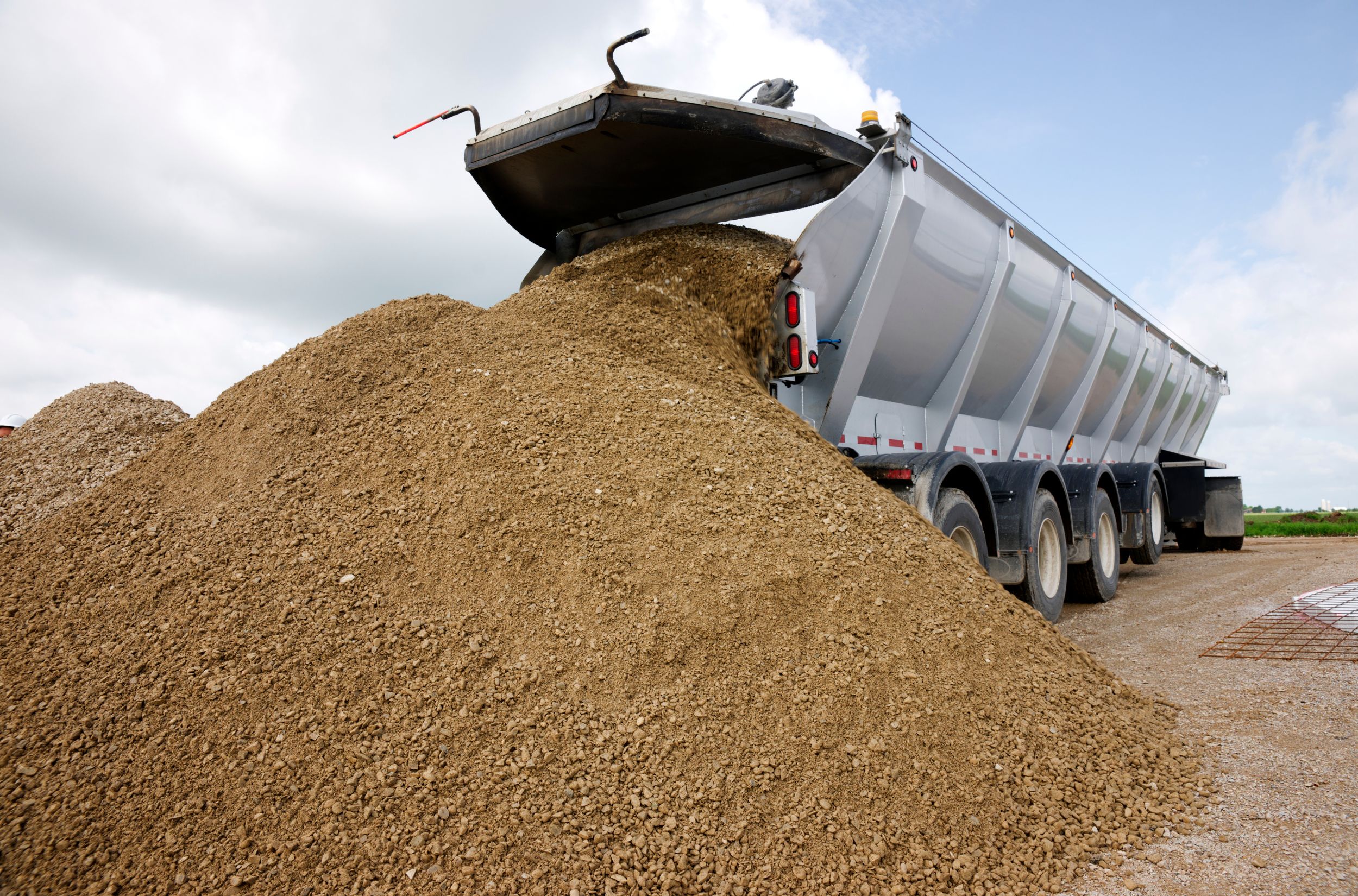 a truck loading gravel into a pile of dirt